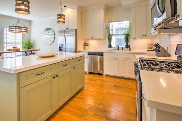 kitchen featuring decorative backsplash, stainless steel appliances, light countertops, and a sink