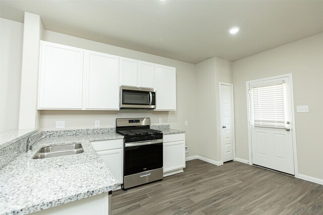 13774 Sunshine Peak Dr, Willis, TX 77318 - kitchen with light wood-style flooring, white cabinets, stainless steel appliances, and a sink
