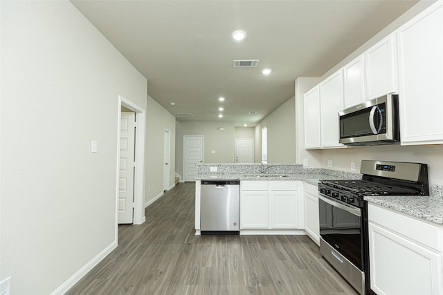 13774 Sunshine Peak Dr, Willis, TX 77318 - kitchen with visible vents, light wood finished floors, a sink, appliances with stainless steel finishes, and white cabinetry
