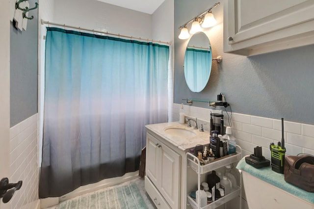 full bathroom featuring tile walls, wainscoting, and vanity