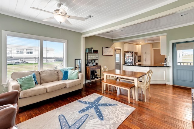 living area with visible vents, a ceiling fan, hardwood / wood-style flooring, crown molding, and baseboards