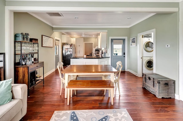 dining space with visible vents, dark wood-style floors, crown molding, and stacked washer / dryer