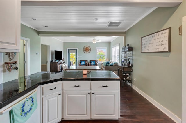 kitchen featuring visible vents, a peninsula, open floor plan, and crown molding