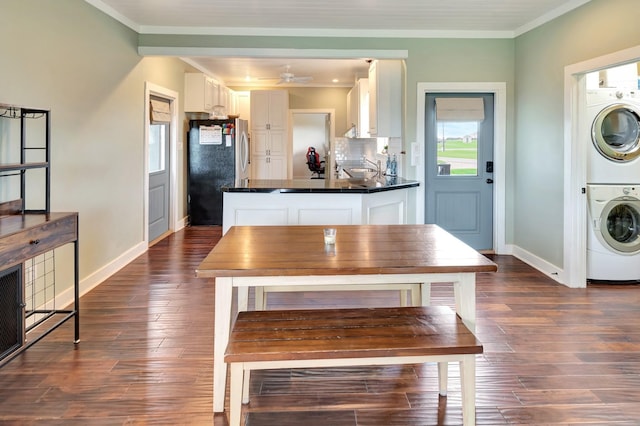 11 Enchanted Ln, Port Alto, TX 77979 - kitchen with estacked washer and dryer, freestanding refrigerator, white cabinets, crown molding, and dark wood-style floors