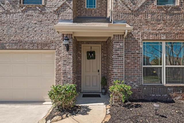 view of exterior entry with brick siding and an attached garage