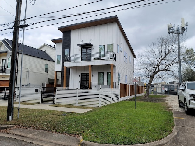 view of front of house featuring a front yard, a balcony, covered porch, and a fenced front yard