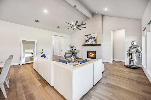 living room with beamed ceiling, visible vents, light wood-type flooring, and a large fireplace