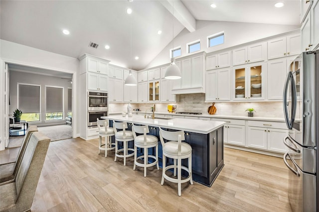 kitchen featuring tasteful backsplash, appliances with stainless steel finishes, white cabinets, and light countertops