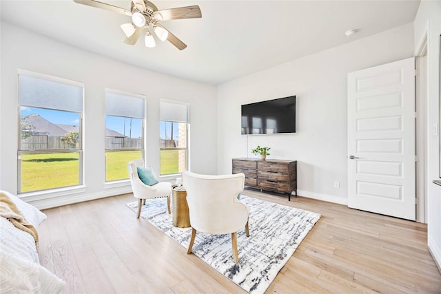 sitting room with light wood finished floors, a ceiling fan, and baseboards