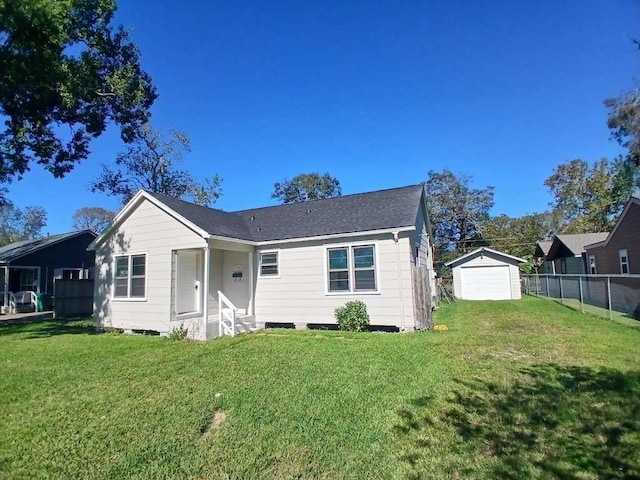 view of front of home with a detached garage, an outbuilding, a front yard, and fence