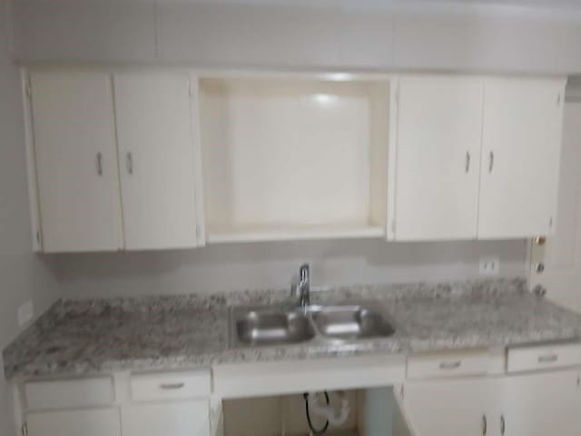 kitchen featuring a sink, white cabinets, and light countertops