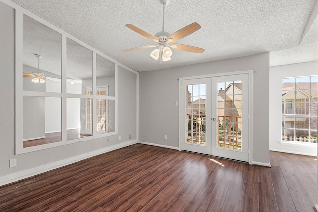 empty room featuring a textured ceiling, wood finished floors, french doors, baseboards, and ceiling fan