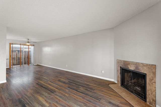 unfurnished living room with a ceiling fan, baseboards, a premium fireplace, dark wood-type flooring, and a textured ceiling