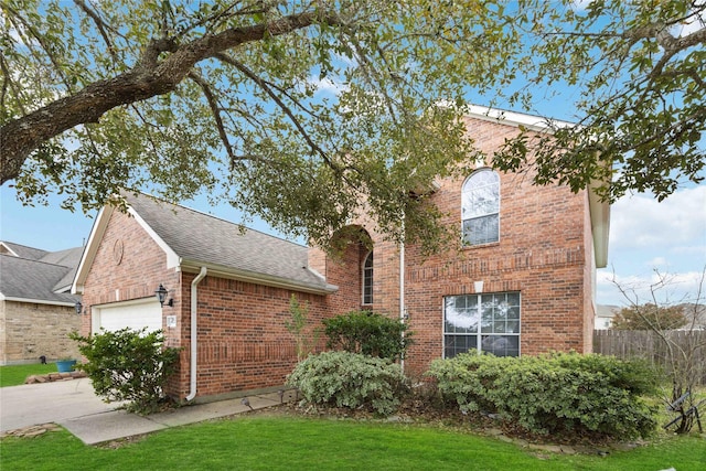 view of front facade featuring driveway, a front lawn, roof with shingles, an attached garage, and brick siding