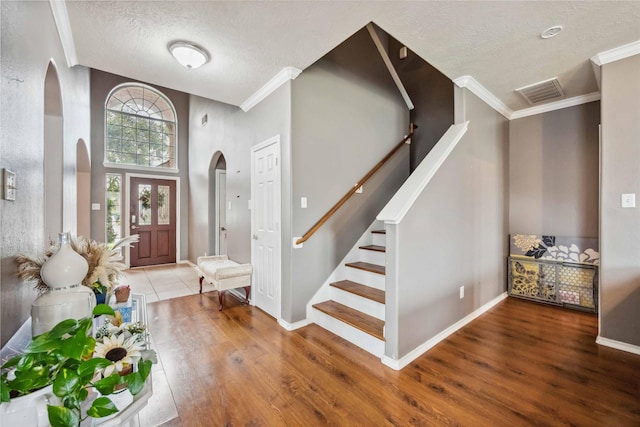 entrance foyer featuring stairs, visible vents, wood finished floors, and arched walkways