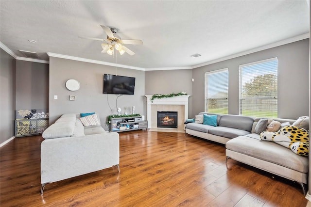 living area featuring crown molding, wood finished floors, visible vents, and a tile fireplace