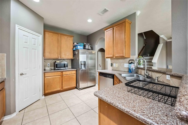 kitchen featuring light tile patterned floors, visible vents, arched walkways, a sink, and stainless steel appliances