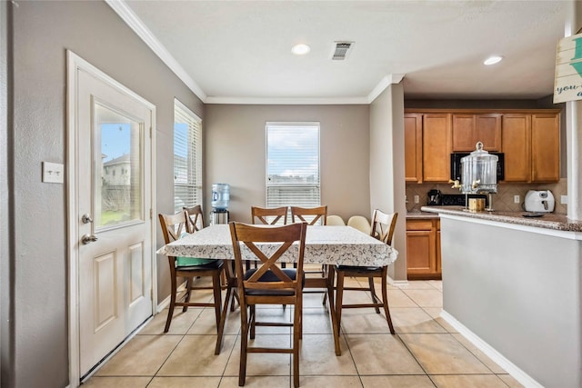 dining room featuring light tile patterned floors, visible vents, crown molding, and baseboards