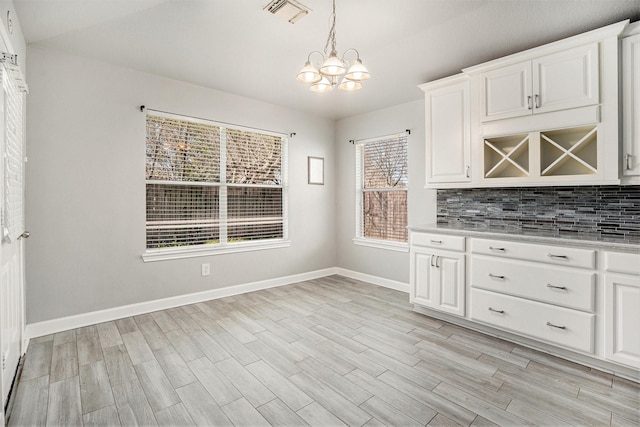 unfurnished dining area featuring light wood-style flooring, baseboards, visible vents, and a chandelier