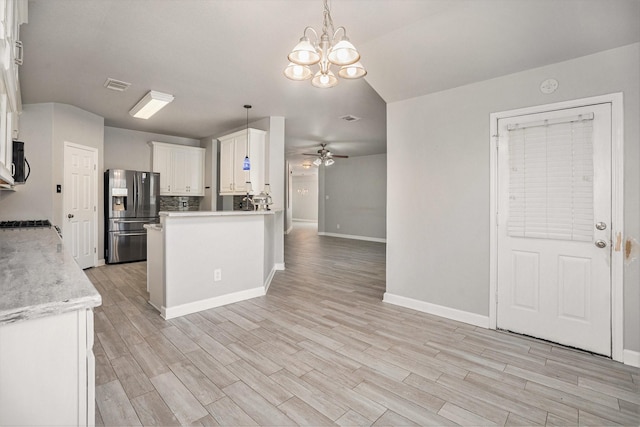 kitchen featuring light wood finished floors, stainless steel fridge with ice dispenser, light countertops, black microwave, and ceiling fan with notable chandelier