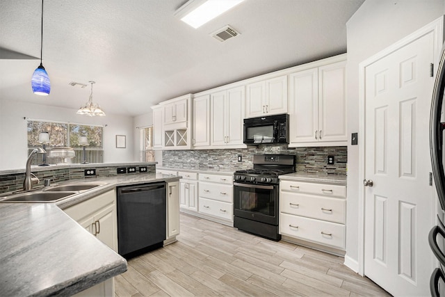 kitchen featuring black appliances, visible vents, backsplash, and a sink