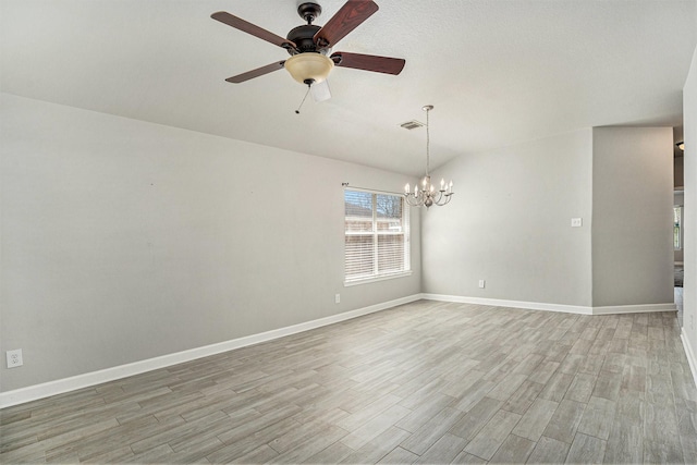 unfurnished room with light wood-type flooring, visible vents, ceiling fan with notable chandelier, baseboards, and lofted ceiling