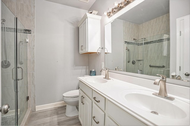 bathroom with a shower stall, wood finished floors, baseboards, and a sink