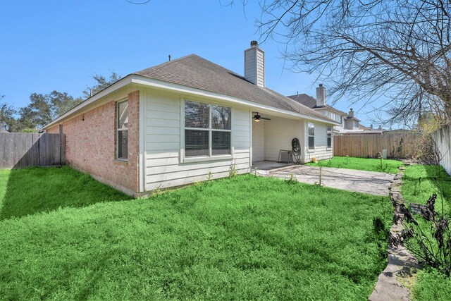 back of property with a patio area, a lawn, a fenced backyard, and a chimney