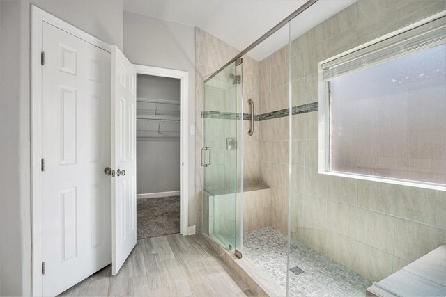 full bathroom featuring a spacious closet, a stall shower, and baseboards