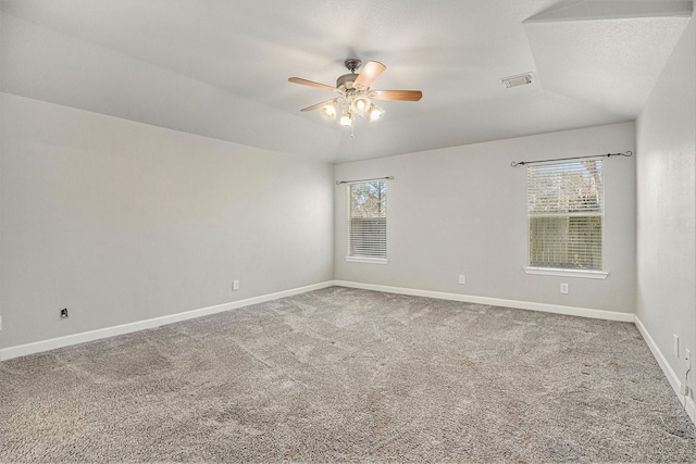 spare room with visible vents, baseboards, ceiling fan, vaulted ceiling, and carpet flooring