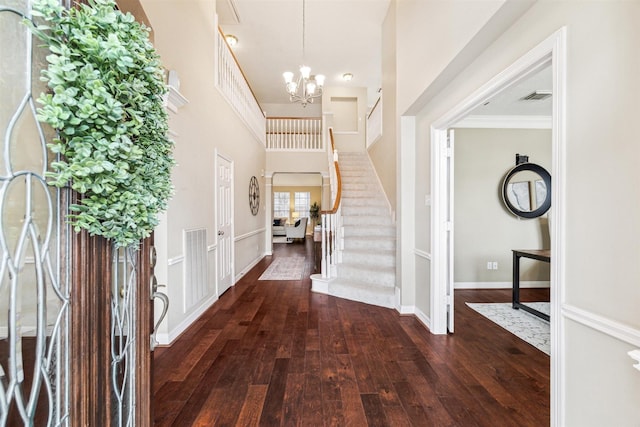 foyer featuring baseboards, visible vents, an inviting chandelier, stairs, and wood-type flooring