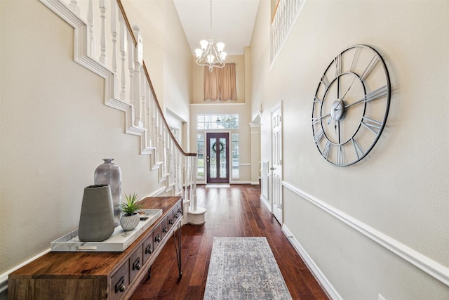 entrance foyer with baseboards, dark wood finished floors, stairs, a towering ceiling, and a notable chandelier