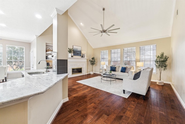 living area featuring a tile fireplace, high vaulted ceiling, dark wood-type flooring, and baseboards