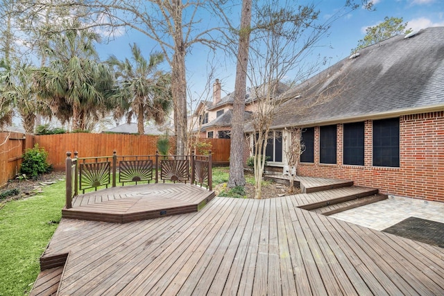 wooden terrace featuring a fenced backyard and a lawn