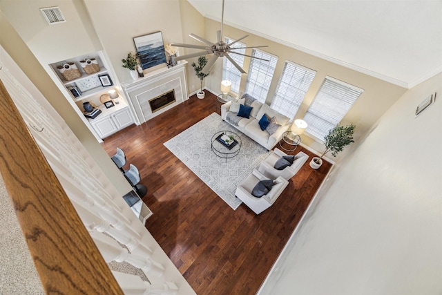 living room featuring visible vents, dark wood-type flooring, lofted ceiling, ornamental molding, and a fireplace