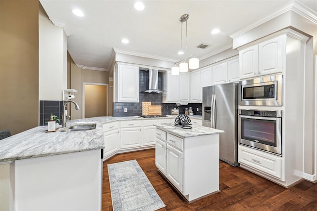 kitchen featuring visible vents, a peninsula, a sink, stainless steel appliances, and wall chimney range hood