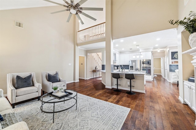 living area featuring visible vents, crown molding, baseboards, stairs, and dark wood-style flooring