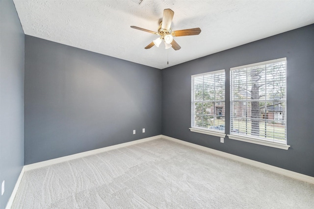 spare room with carpet flooring, ceiling fan, a textured ceiling, and baseboards