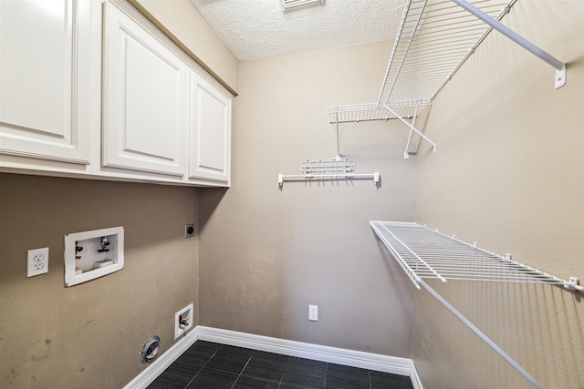 washroom featuring electric dryer hookup, washer hookup, a textured ceiling, cabinet space, and baseboards