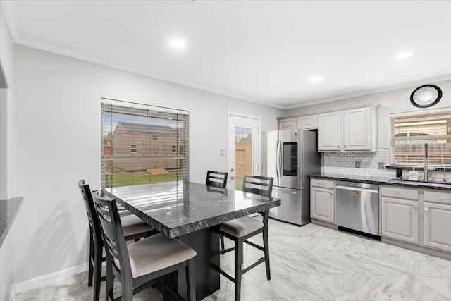 kitchen featuring ornamental molding, a sink, backsplash, appliances with stainless steel finishes, and baseboards