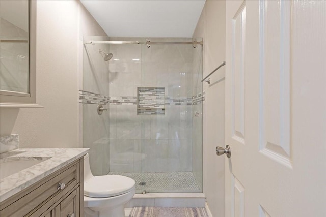 bathroom with a shower stall, toilet, and vanity