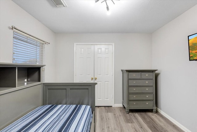 bedroom featuring visible vents, baseboards, a closet, and wood finished floors