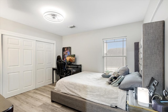 bedroom featuring light wood-style floors, visible vents, and a closet