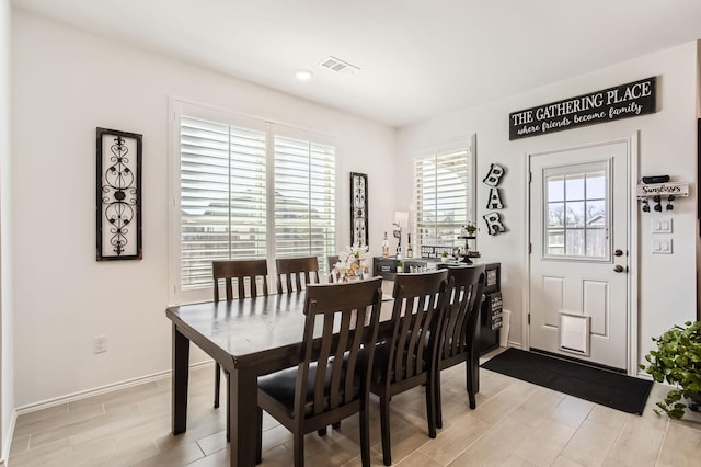 dining space with visible vents, baseboards, and wood tiled floor