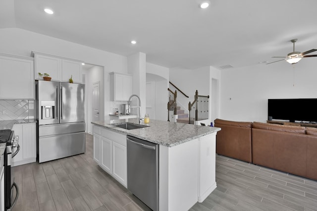 kitchen featuring open floor plan, stainless steel appliances, white cabinetry, a ceiling fan, and a sink