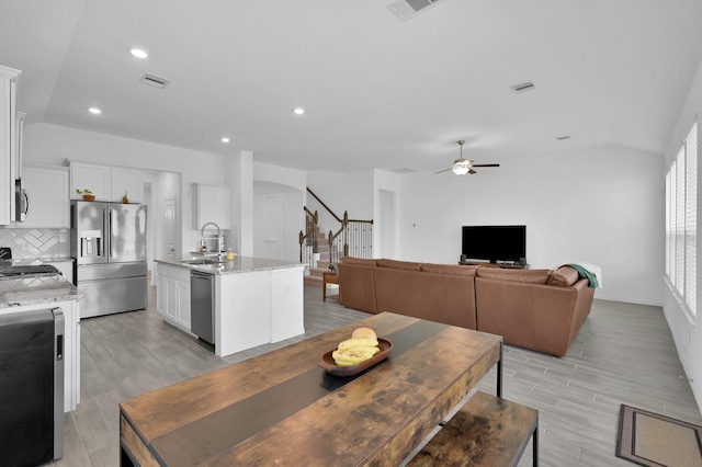 dining room with light wood finished floors, visible vents, lofted ceiling, and a ceiling fan