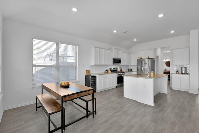 kitchen featuring decorative backsplash, light stone counters, white cabinetry, and appliances with stainless steel finishes