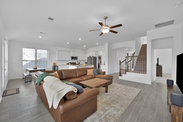 living room with arched walkways, visible vents, ceiling fan, and wood tiled floor