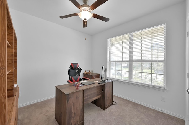 office area featuring baseboards, light carpet, and ceiling fan