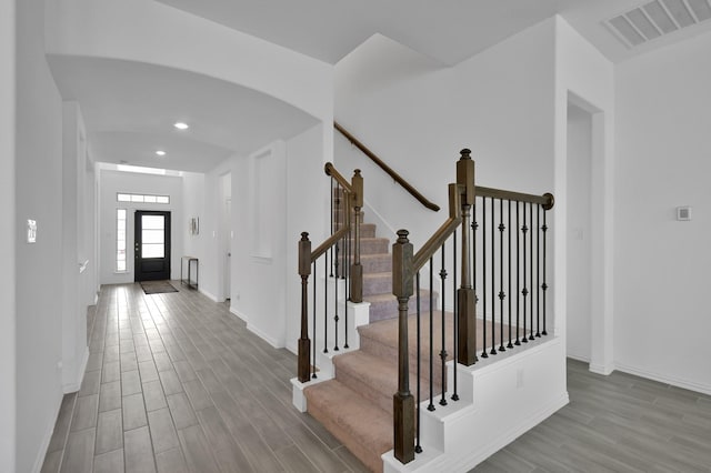 interior space featuring arched walkways, visible vents, baseboards, and wood finished floors